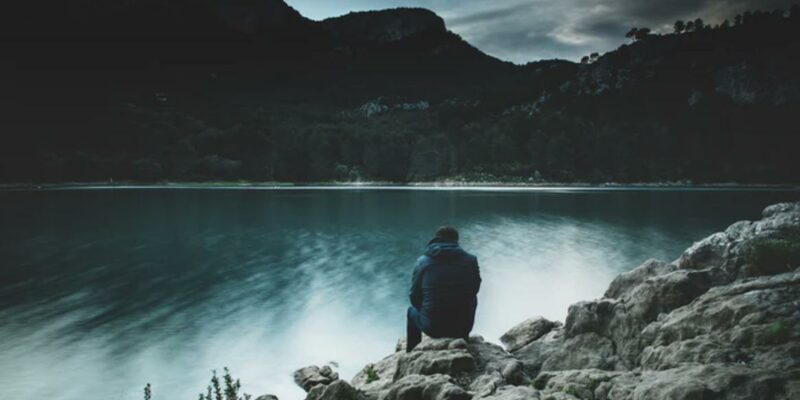 Man sitting on rocks at lake